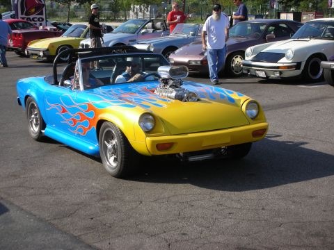 1998 Ford Crown Victoria - A custom hot rod with a prominent supercharger and flame graphics is parked among other vehicles.