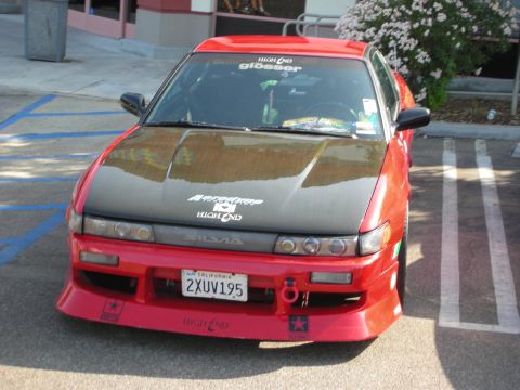 1998 Ford Crown Victoria - A red sports car with a black hood and custom body kit is parked in a lot.
