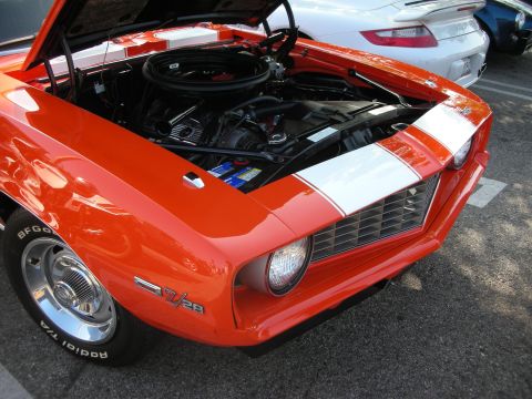 1998 Ford Crown Victoria - This orange 1969 Camaro Z/28 displays its engine, with white racing stripes and other vehicles visible in the background.