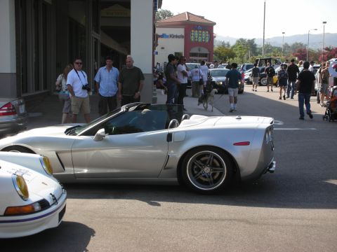 1998 Ford Crown Victoria - A silver convertible sports car is parked on a street with people gathered around.