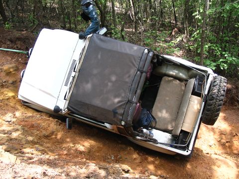 1987 Suzuki Samurai - A white 1987 Suzuki Samurai is shown tipped on its side on a wooded dirt trail.