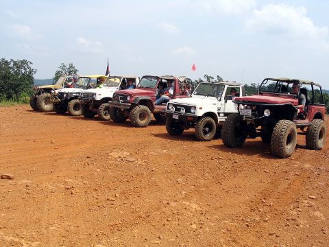 1987 Suzuki Samurai - A group of Suzuki Samurai off-road vehicles are lined up on a dirt trail under a clear sky.