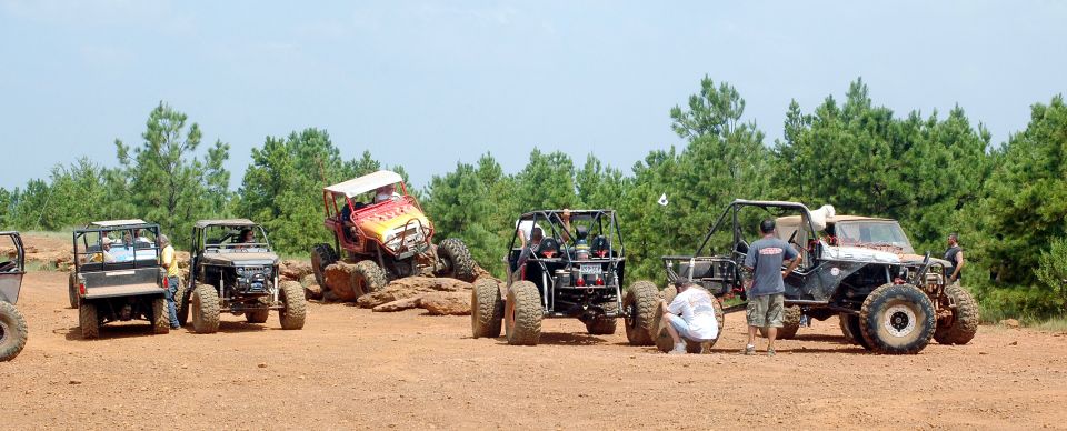 Off-road vehicles on dirt terrain with trees in background