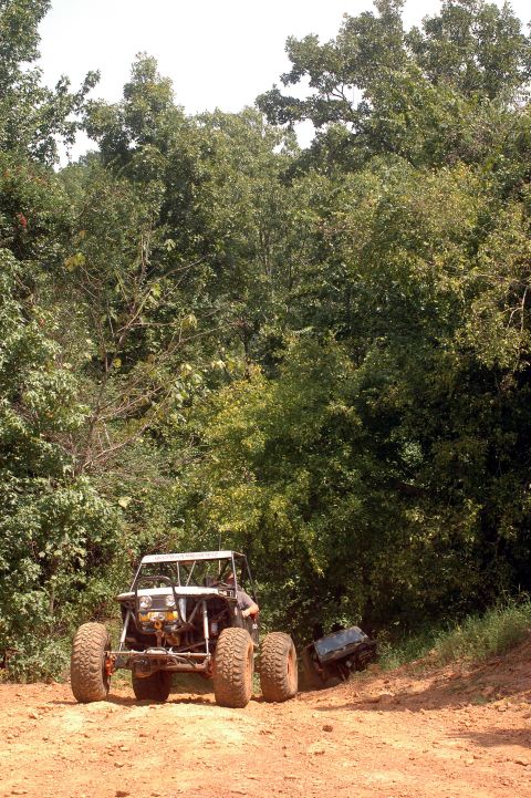 1987 Suzuki Samurai - A custom-built off-road buggy navigates a dirt trail surrounded by dense foliage.