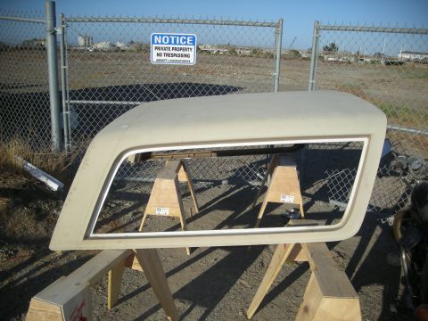 1991 Ford Bronco - A tan Ford Bronco hardtop is displayed on sawhorses in front of a chain-link fence with a "Notice Private Property" sign.