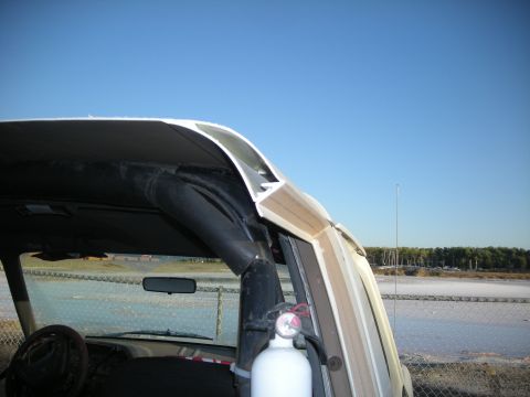 1991 Ford Bronco - The interior of a vehicle is visible, a fire extinguisher and a roll bar against a clear blue sky.