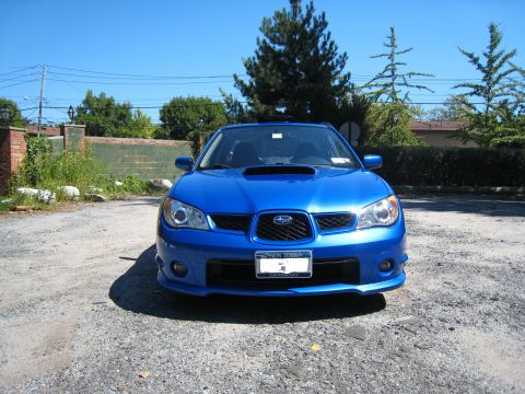 2007 Subaru Impreza - Front view of a blue 2007 Subaru Impreza parked on a gravel lot under a clear blue sky.