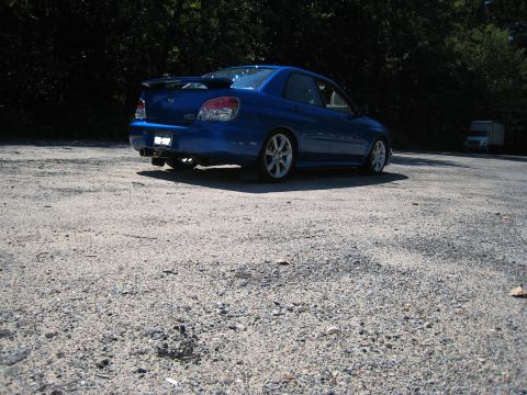2007 Subaru Impreza - Rear view of a blue 2007 Subaru Impreza sedan parked on a gravel lot.