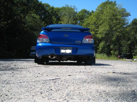 2007 Subaru Impreza - The rear of a blue Subaru WRX is visible, parked on a gravel surface with trees in the background.