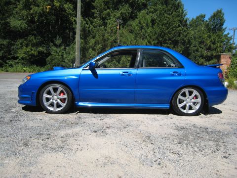 2007 Subaru Impreza - The blue Subaru Impreza sedan is shown from the side, with red brake calipers visible behind the wheels.