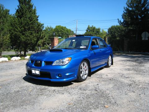 2007 Subaru Impreza - This blue Subaru Impreza sedan is parked on a gravel surface under a clear blue sky.
