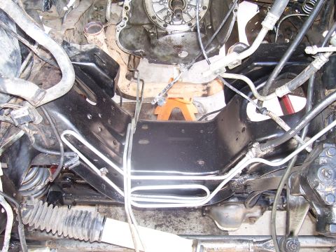 1991 Ford Bronco - Underside view of an engine bay, showing the frame and various hoses, with an orange jack stand visible.