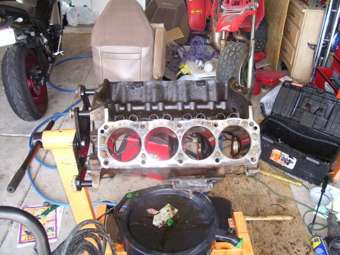 1991 Ford Bronco - An engine block is disassembled and placed on a stand, with other vehicles and tools around it.