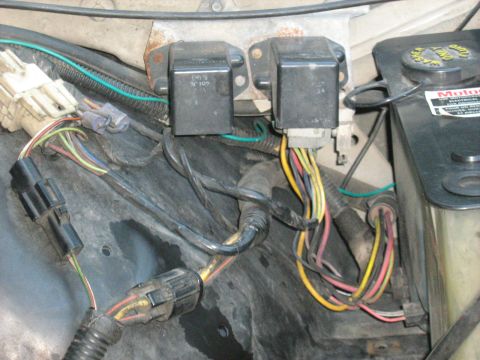 1988 Mercury Grand Marquis - Close-up of electrical relays and wiring harness in a vehicle's engine bay.