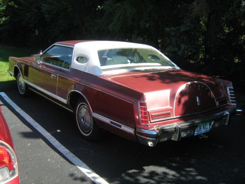 1988 Mercury Grand Marquis - Rear view of a maroon Lincoln Continental Mark VII, showing its distinctive continental kit and vinyl roof.