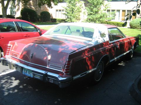 1988 Mercury Grand Marquis - A red 1977 Lincoln Continental Mark V is parked next to a red sedan.