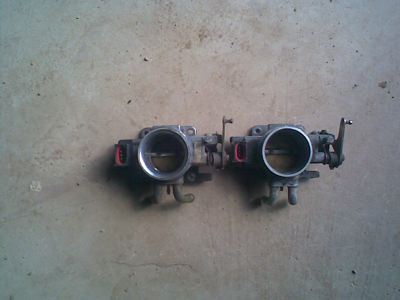 Two throttle bodies on a concrete surface