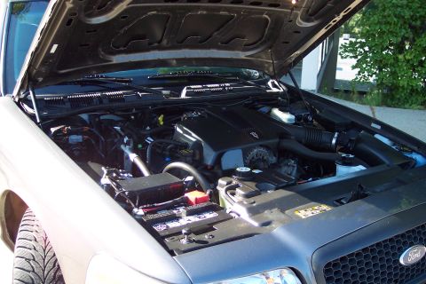 2001 Ford Crown Victoria - The engine bay of a 2003 Ford Crown Victoria is visible with the hood raised, revealing the engine components and battery.