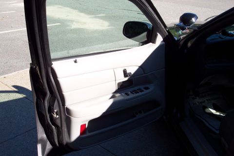2001 Ford Crown Victoria - The interior of a 2001 Ford Crown Victoria is visible, focusing on the driver's side door panel and the dashboard area.