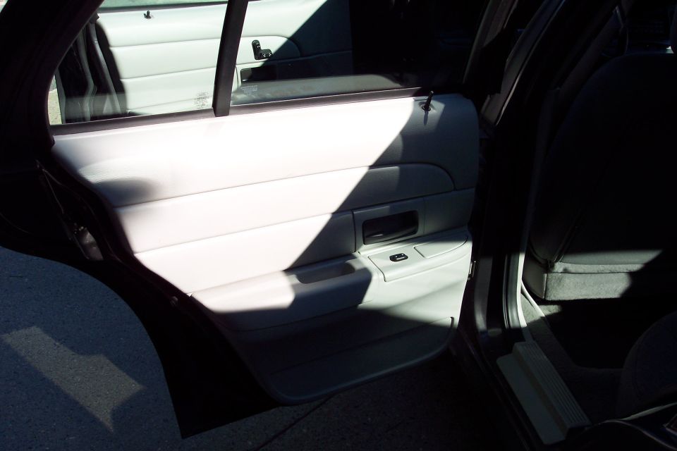 Interior shot of a car's front passenger door panel and seat. Sunlight creates a strong shadow across the door