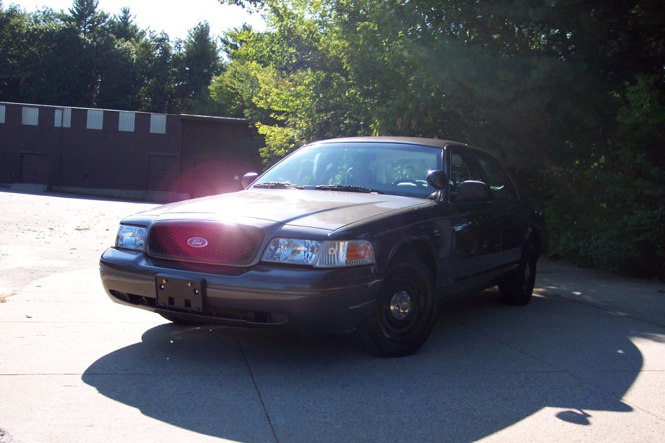 Dark sedan, 3/4 front view. Ford emblem visible on grille