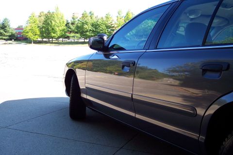 2001 Ford Crown Victoria - Side profile of a dark 2001 Ford Crown Victoria, captured from a low angle.