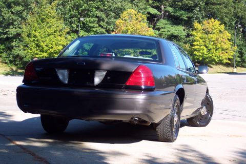 2001 Ford Crown Victoria - A black Ford Crown Victoria Police Interceptor is parked outdoors, showing its rear end and one side.