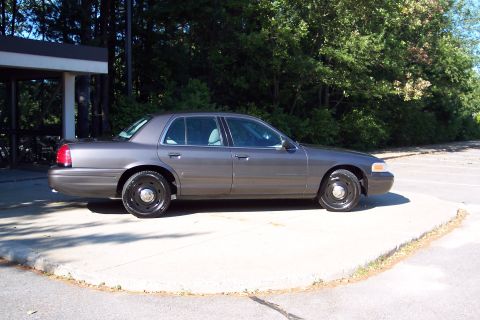 2001 Ford Crown Victoria - Side profile of a gray 2001 Ford Crown Victoria with black steel wheels.
