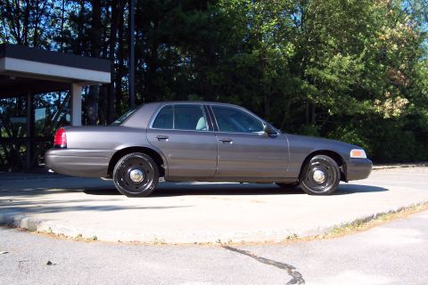 2001 Ford Crown Victoria - This Ford Crown Victoria, likely a 2003 model, is shown from the side with black steel wheels and a gray exterior.