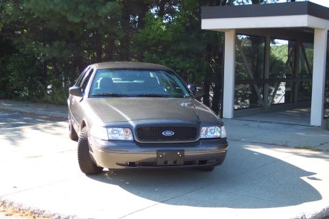 2001 Ford Crown Victoria - A gray Ford Crown Victoria is parked in front of a building with large glass windows.