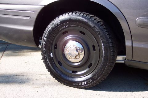 2001 Ford Crown Victoria - The wheel features a black steel rim and a chrome hubcap with a Ford logo, fitted with a Goodyear Eagle GRIP tire.