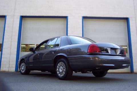 2001 Ford Crown Victoria - Rear quarter view of a 2001 Ford Crown Victoria parked outside a building with garage doors.