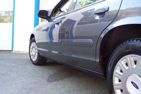 2001 Ford Crown Victoria - Side profile of a gray 2001 Ford Crown Victoria, showing its body style and chrome wheels.