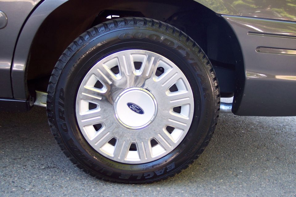 2001 Ford Crown Victoria wheel with hubcap and Goodyear Eagle tire, side view of fender
