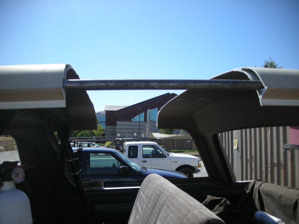 Interior view of a 1991 Ford Bronco showing a roll bar, seats, and a blue truck and white pickup outside
