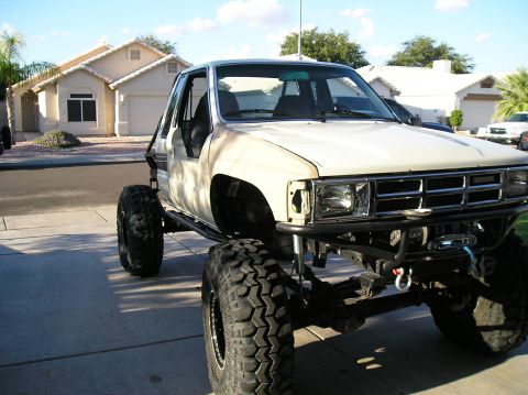 1986 Toyota Hilux - This heavily modified pickup truck features oversized tires and a custom roll cage, suggesting off-road use.