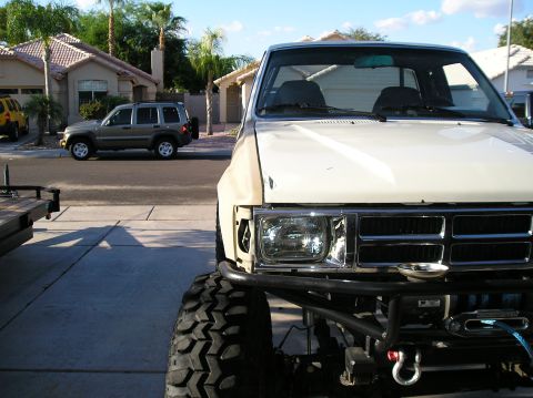 1986 Toyota Hilux - A modified white pickup truck is parked in a driveway, with a Jeep Liberty visible on the street.