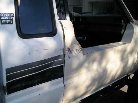 1986 Toyota Hilux - Driver's side door of a 1986 Toyota Hilux shows significant damage and a "TOYOTA 4WD EFI" badge.