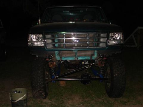 1996 Ford F-150 - This lifted Ford truck shows its front end, with a prominent chrome grille and visible suspension modifications.