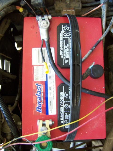 1991 Ford Bronco - Close-up view of a red Duralast automotive battery under the hood of a vehicle.