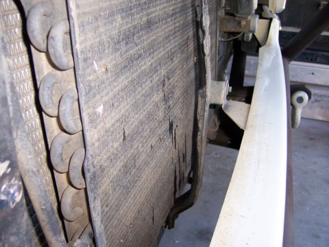 1991 Ford Bronco - Close-up view of a dirty and damaged transmission cooler, likely from a vehicle.
