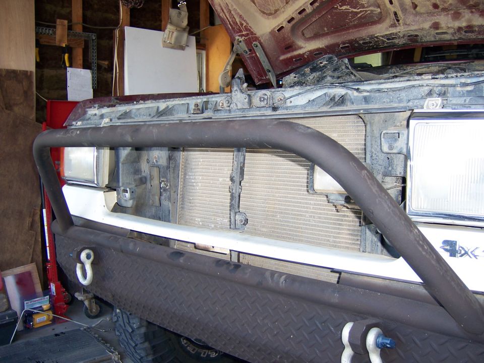 Front of a truck, hood open, showing grille and bumper with tow hooks