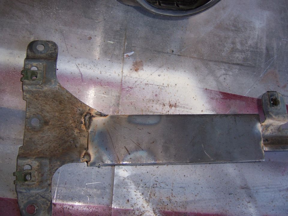 Welded metal bracket with mounting holes and rust