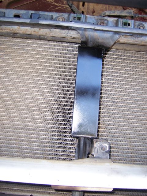 1991 Ford Bronco - Close-up view of a vehicle's radiator and a black mounting bracket.