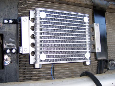 1991 Ford Bronco - A transmission cooler is mounted in front of a vehicle's radiator, with visible wiring and mounting brackets.
