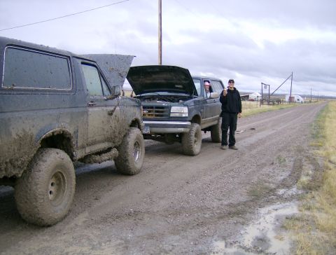 1990 Ford Bronco - Two 1990 Ford Broncos are parked on a dirt road with their hoods open.