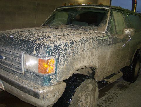 1990 Ford Bronco - This SUV is heavily covered in mud, obscuring its original color and details.