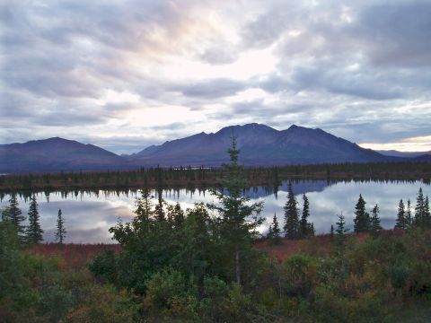 2000 Ford E350 - A vast mountain range is mirrored in a tranquil lake, surrounded by evergreen trees and autumnal foliage.