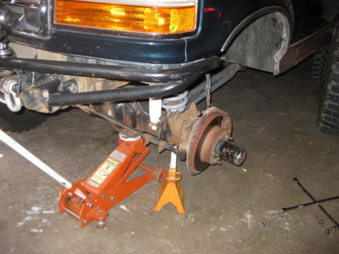 1995 Ford Bronco - Front wheel hub assembly of a dark blue SUV, supported by a jack and stand.