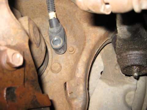 1995 Ford Bronco - Close-up view of an ABS sensor mounted on a heavily rusted suspension component.